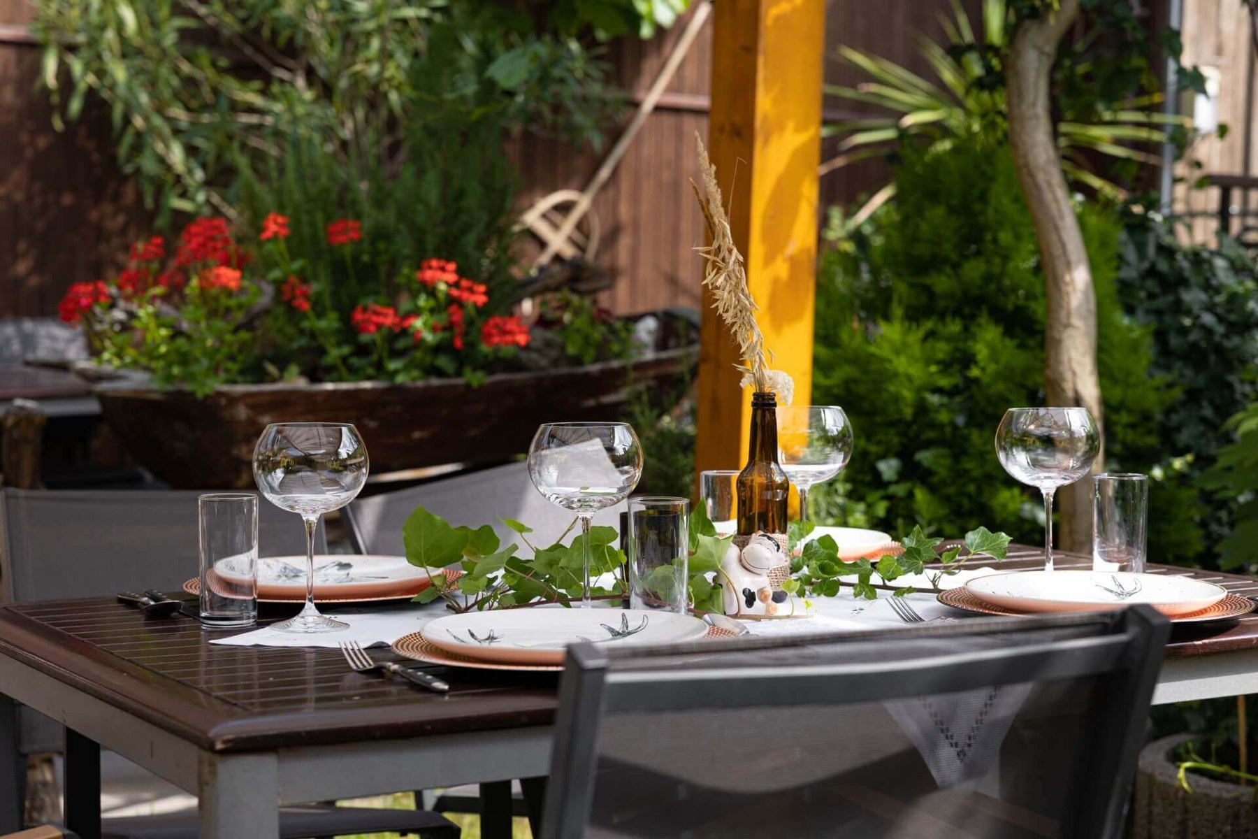 Terrasse der Bezirks Alm mit Sonnensegeln und gedeckten Tischen im Garten
